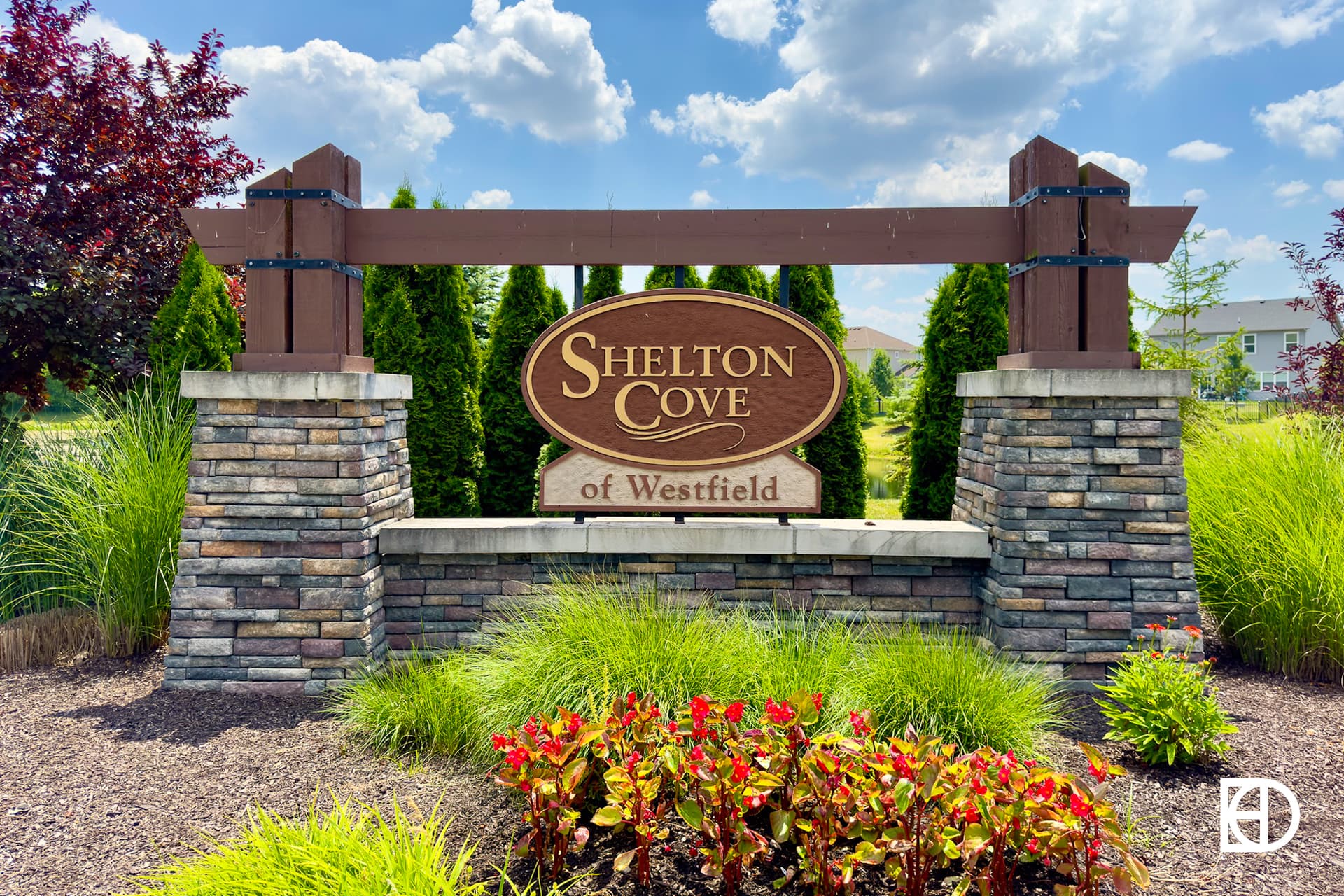 Entrance sign to Shelton Cove of Westfield with stone and wood, with flowers in the front.