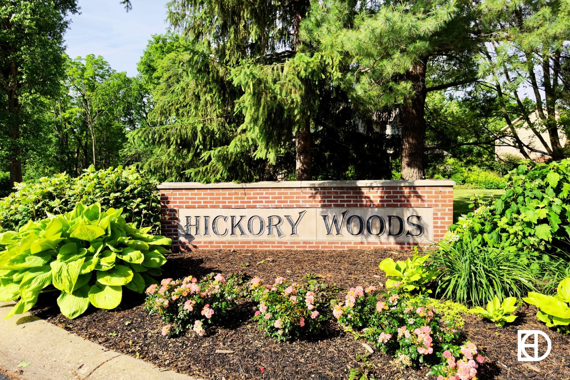 Exterior photo of Hickory Woods, showing signage on small brick wall and landscaping