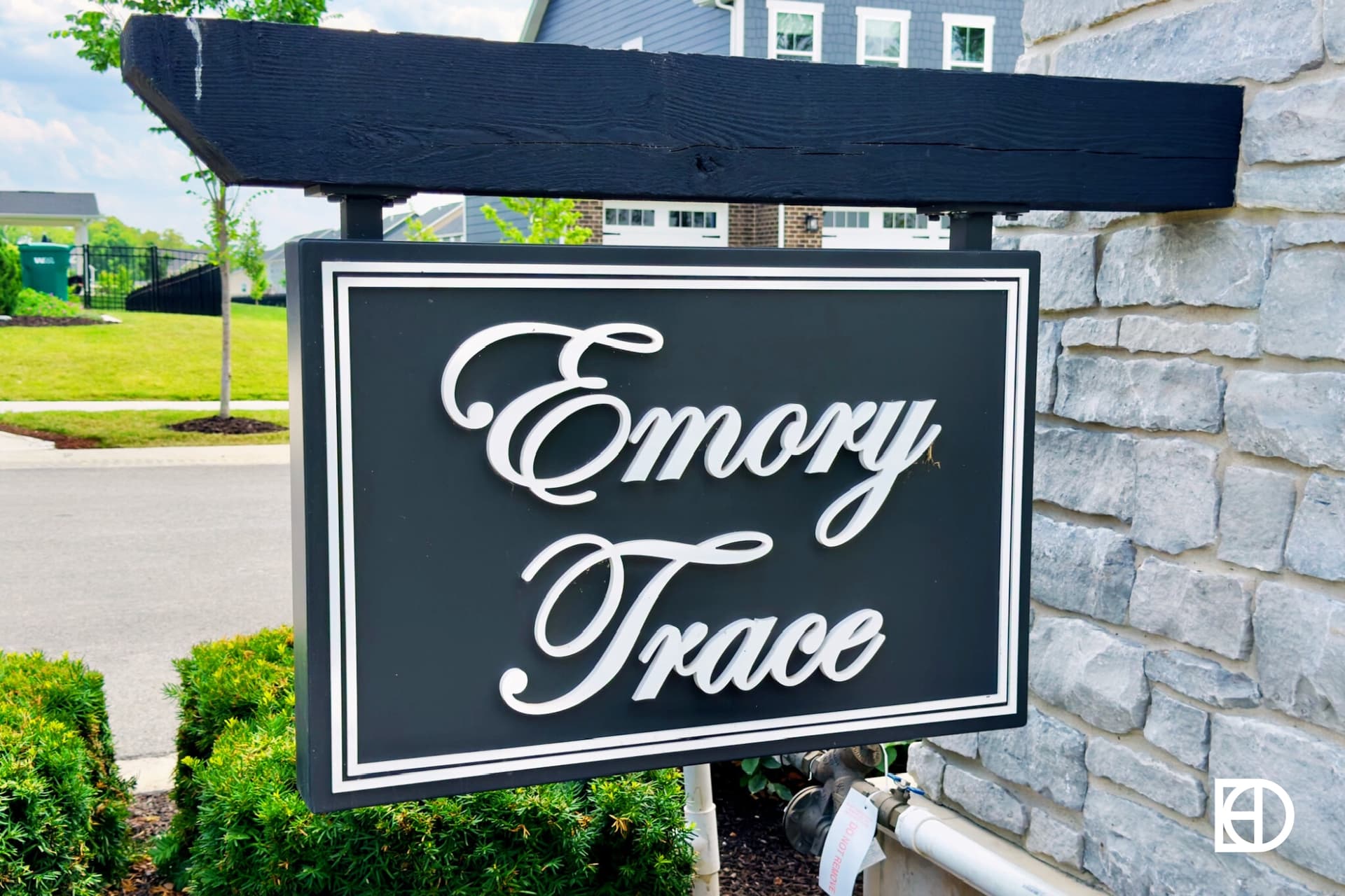 Close up photo of Emory Trace entrance sign hanging on stone column.