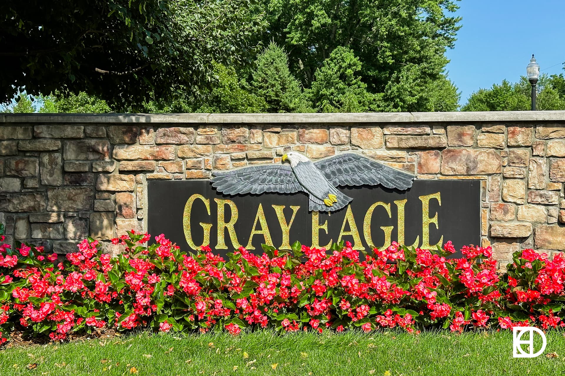 Exterior photo of Gray Eagle, showing signage on stone wall and landscaping