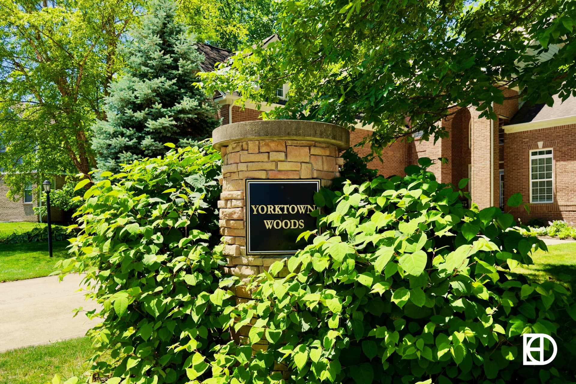 Stone column entrance sign to Yorktown Woods flanked by ivy.