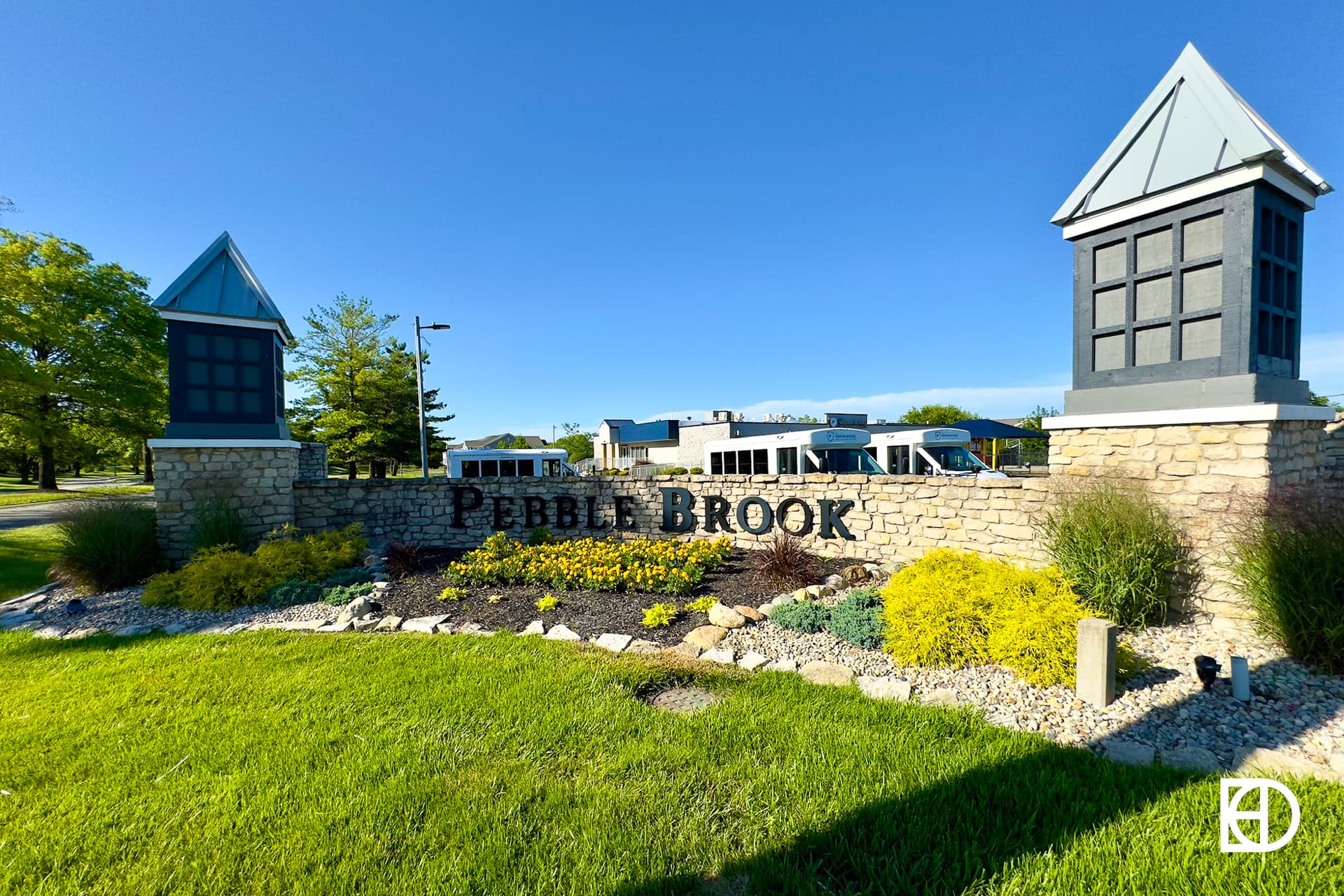 Entrance sign to Pebble Brook in stone with landscaping.