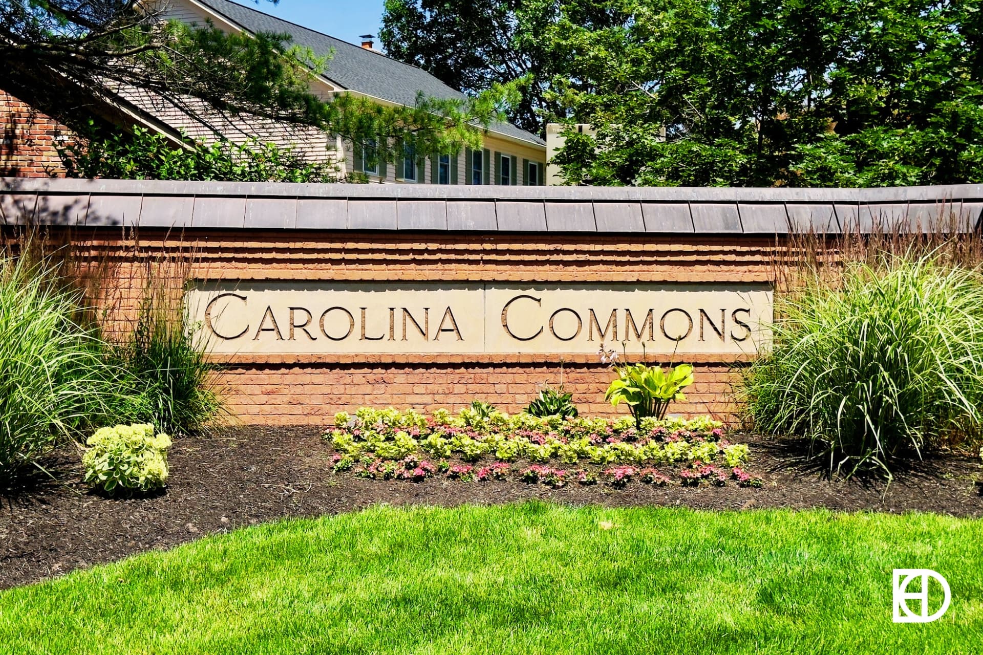 Brick and stone entrance sign to Carolina Commons with decorative grasses and flowers in front.