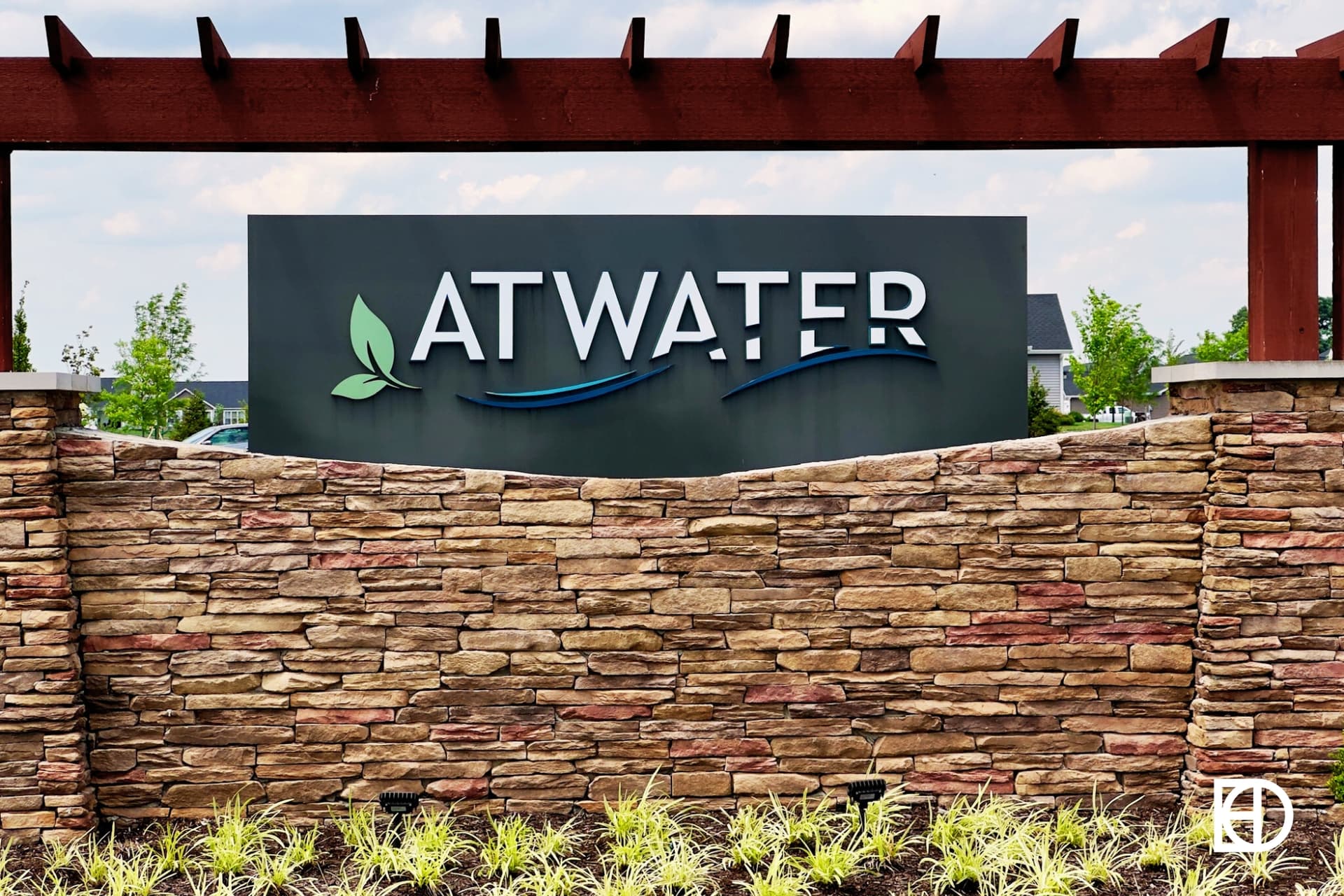 Atwater entrance sign on stone wall with wood pergola.