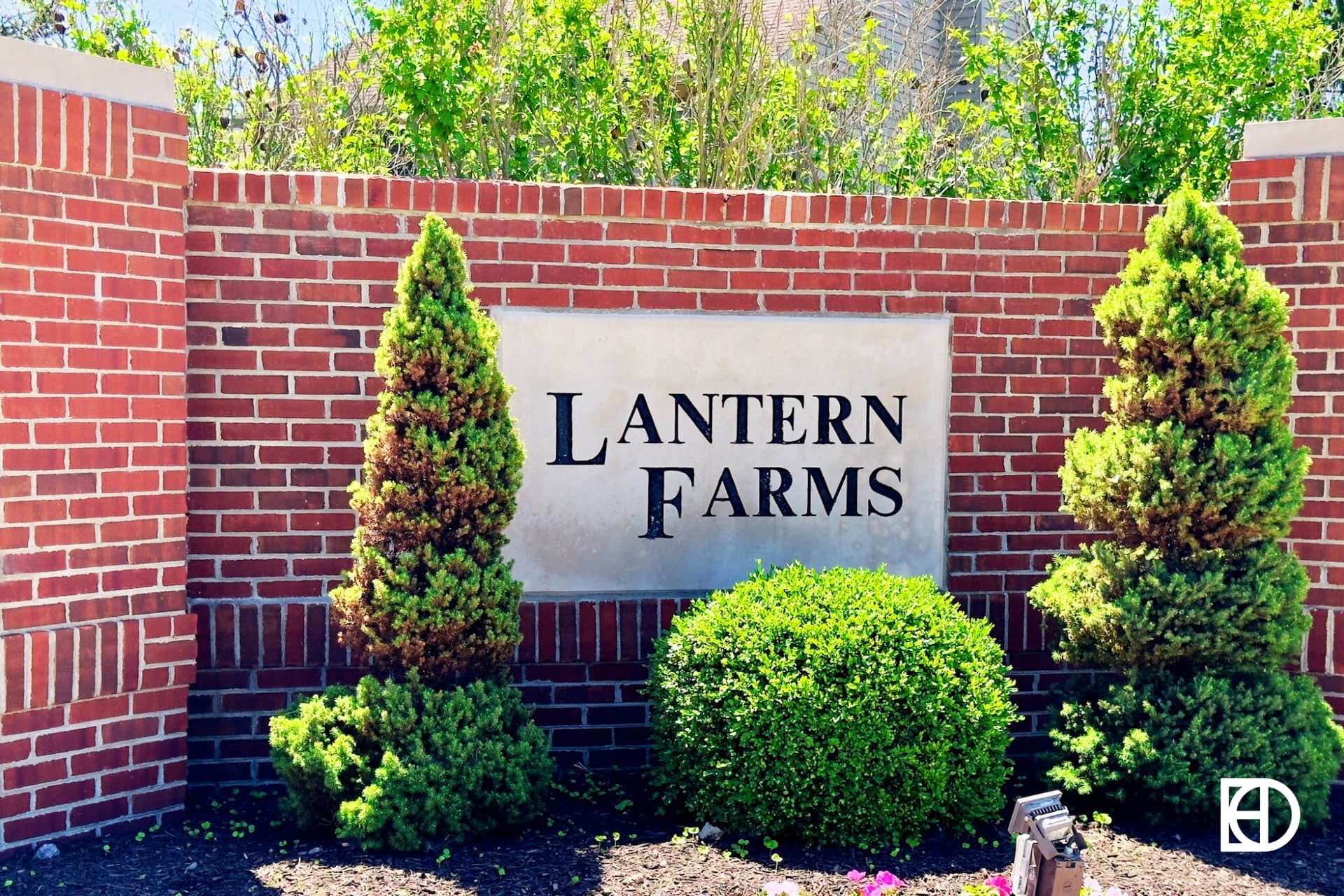 Exterior photo of Lantern Farms, showing signage on small brick wall and landscaping