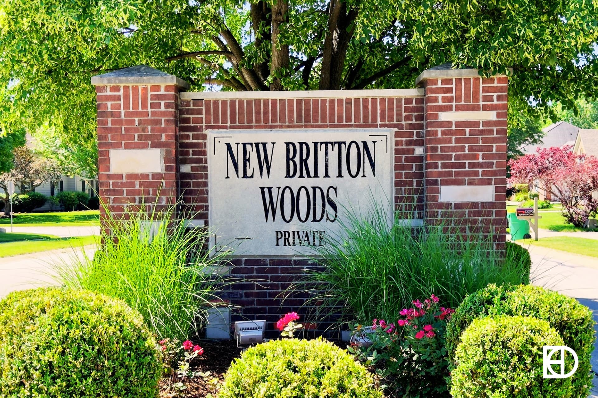 Exterior photo of New Britton Woods, showing signage on low brick wall and landscaping