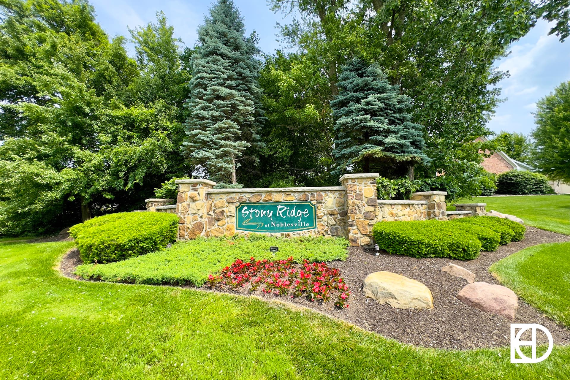 Stone Ridge of Naperville neighborhood entrance sign surrounded by landscaped bushes, flowers, rocks, and trees.