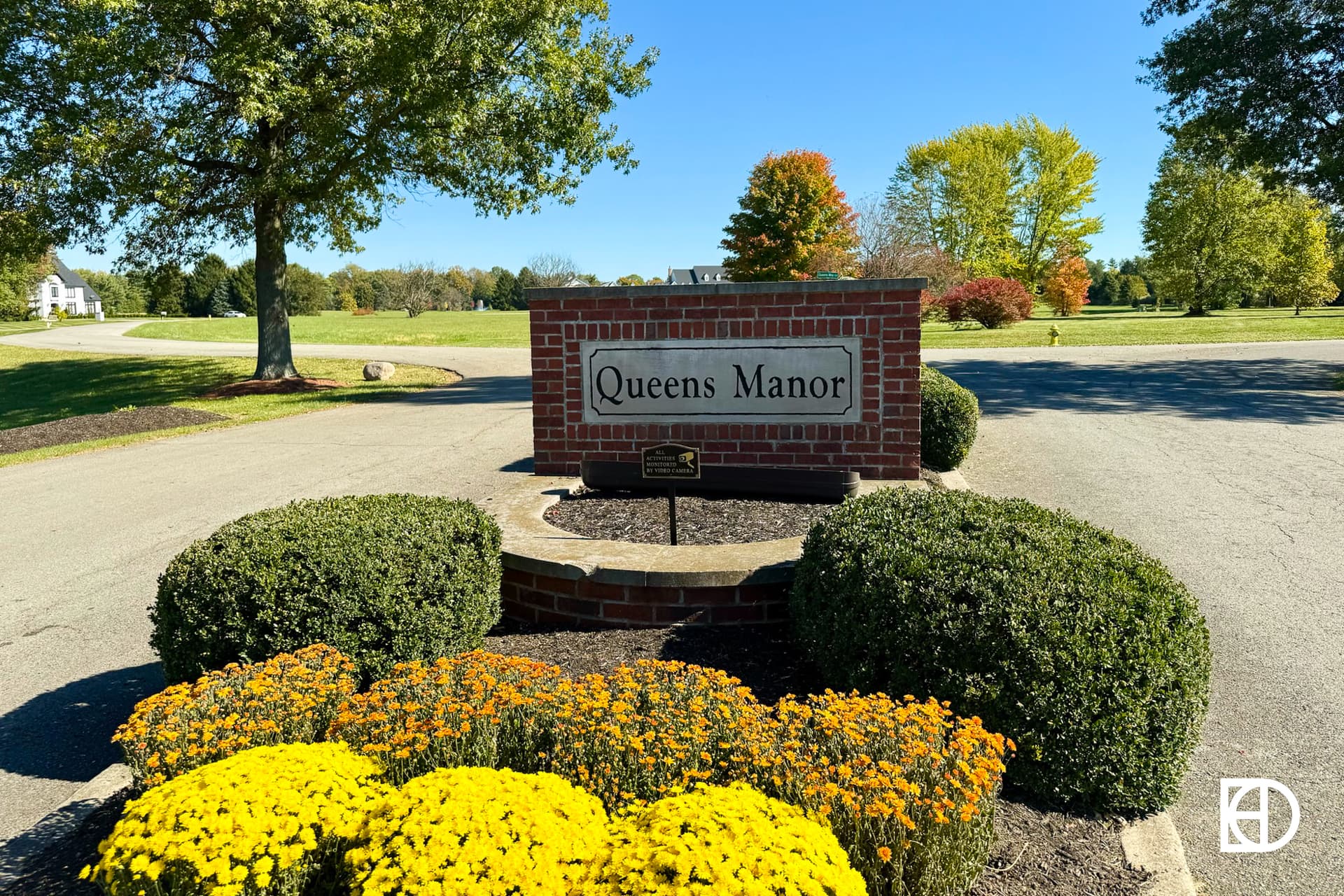 Exterior photo of Queen's Manor, showing signage and landscaping