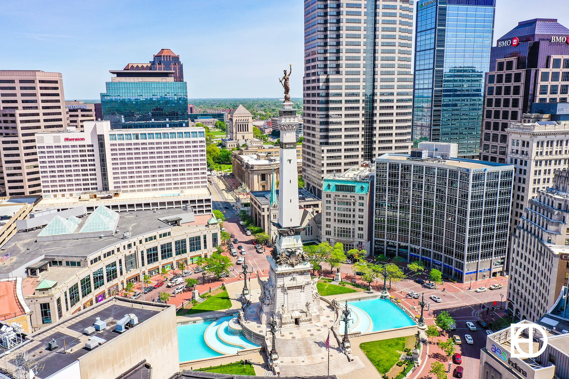 Aerial view of Monument Circle in downtown Indianapolis, showing the Soldiers and Sailors Monument surrounded by tall buildings and city streets.