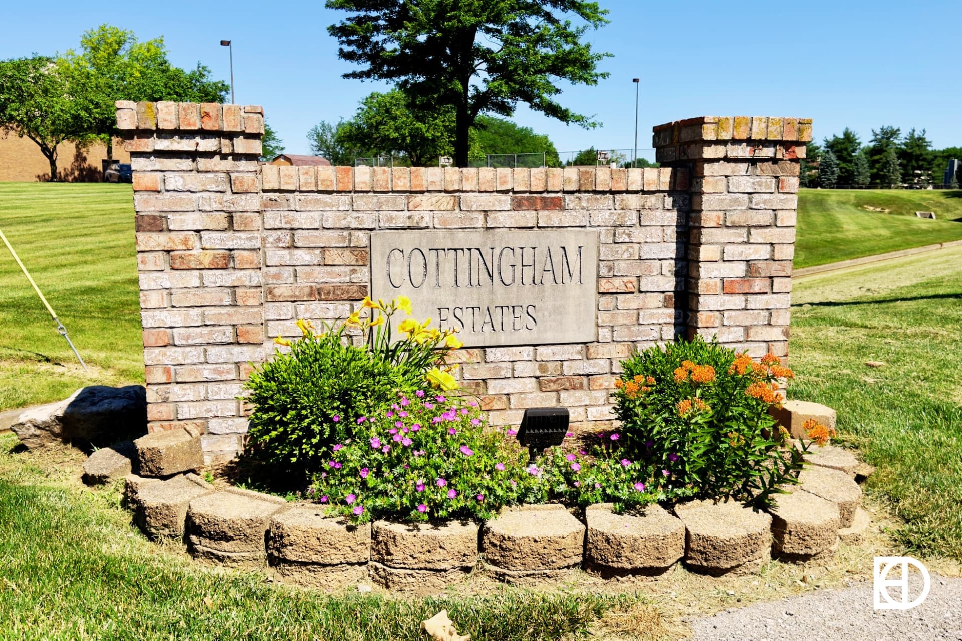 Stone wall with engraving reading "Cottingham Estates" and landscaping around