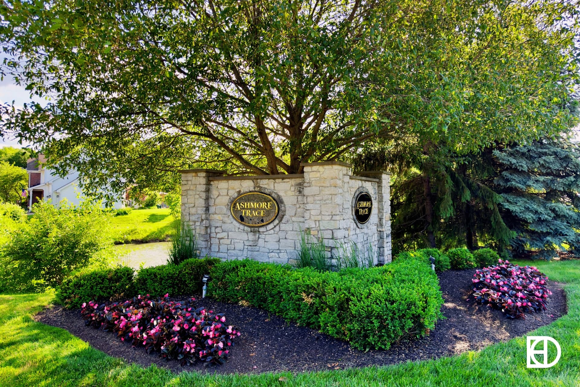 Ashmore Trace stone entrance sign with shrubs, flowers and trees.