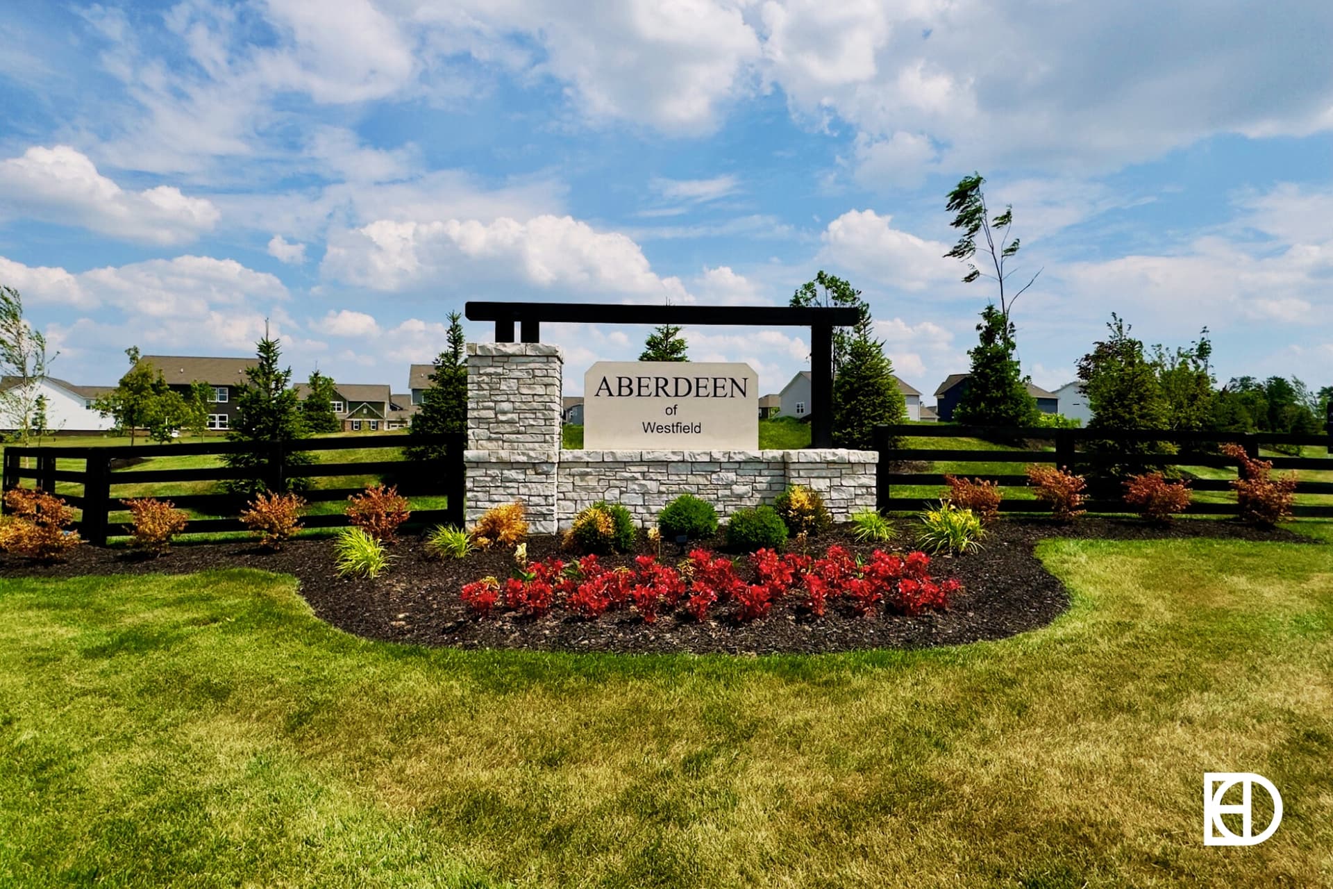 Stone and wood entrance sign to Aberdeen neighborhood with flowers bed around and fence to each side.