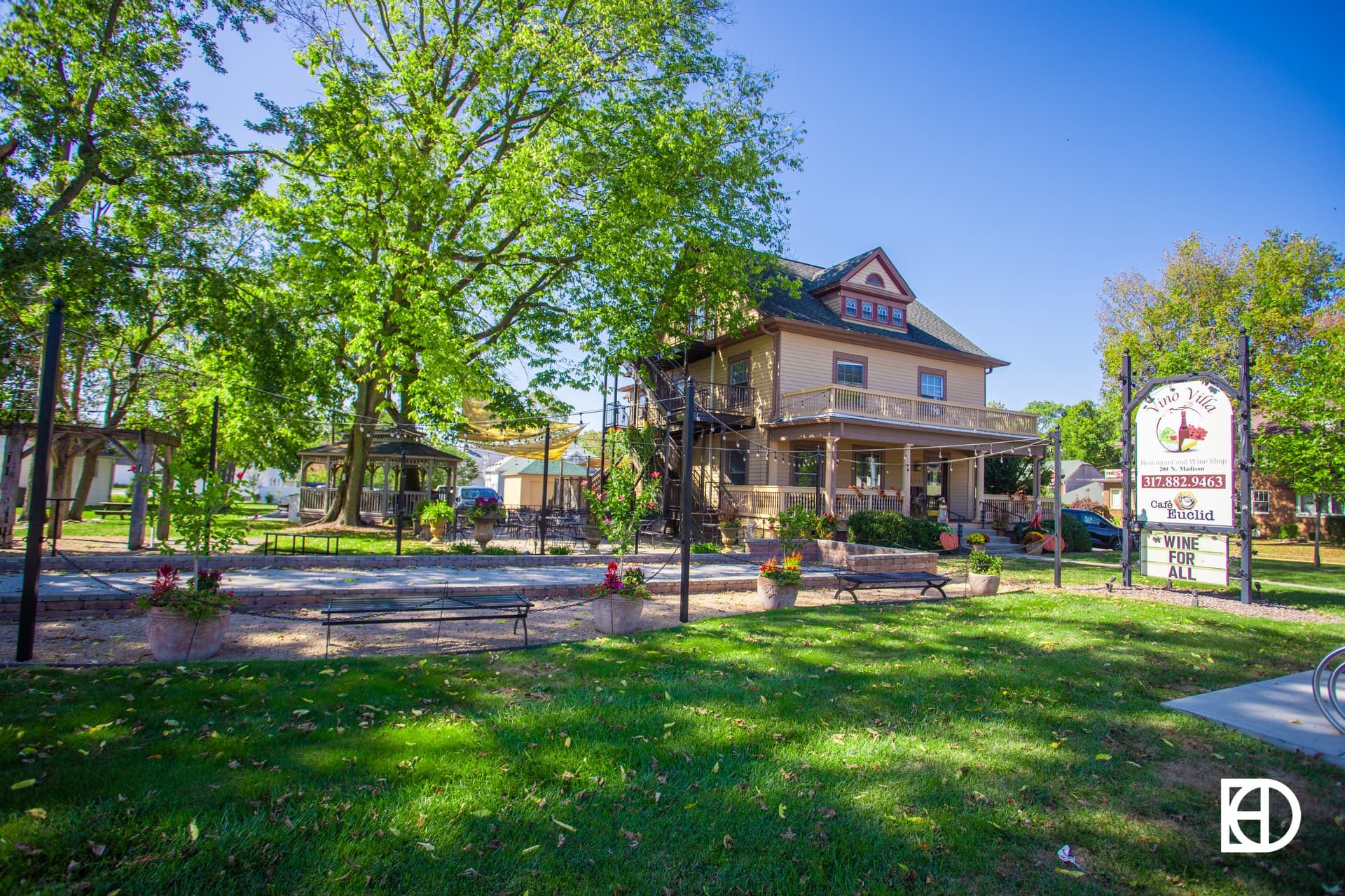 Exterior photo of Vino Villa, showing patio, building, green space, trees, and landscaping